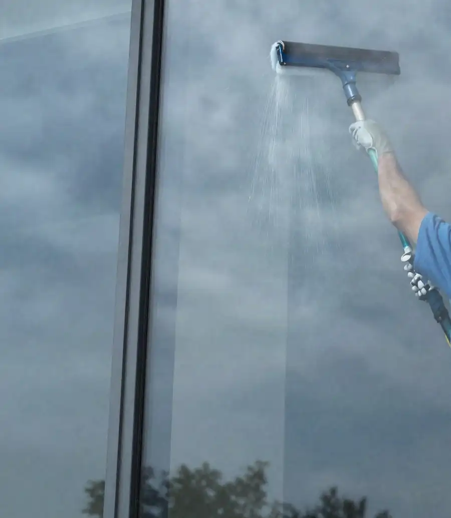 Cleaning tall commercial windows with a pole-mounted scrubber