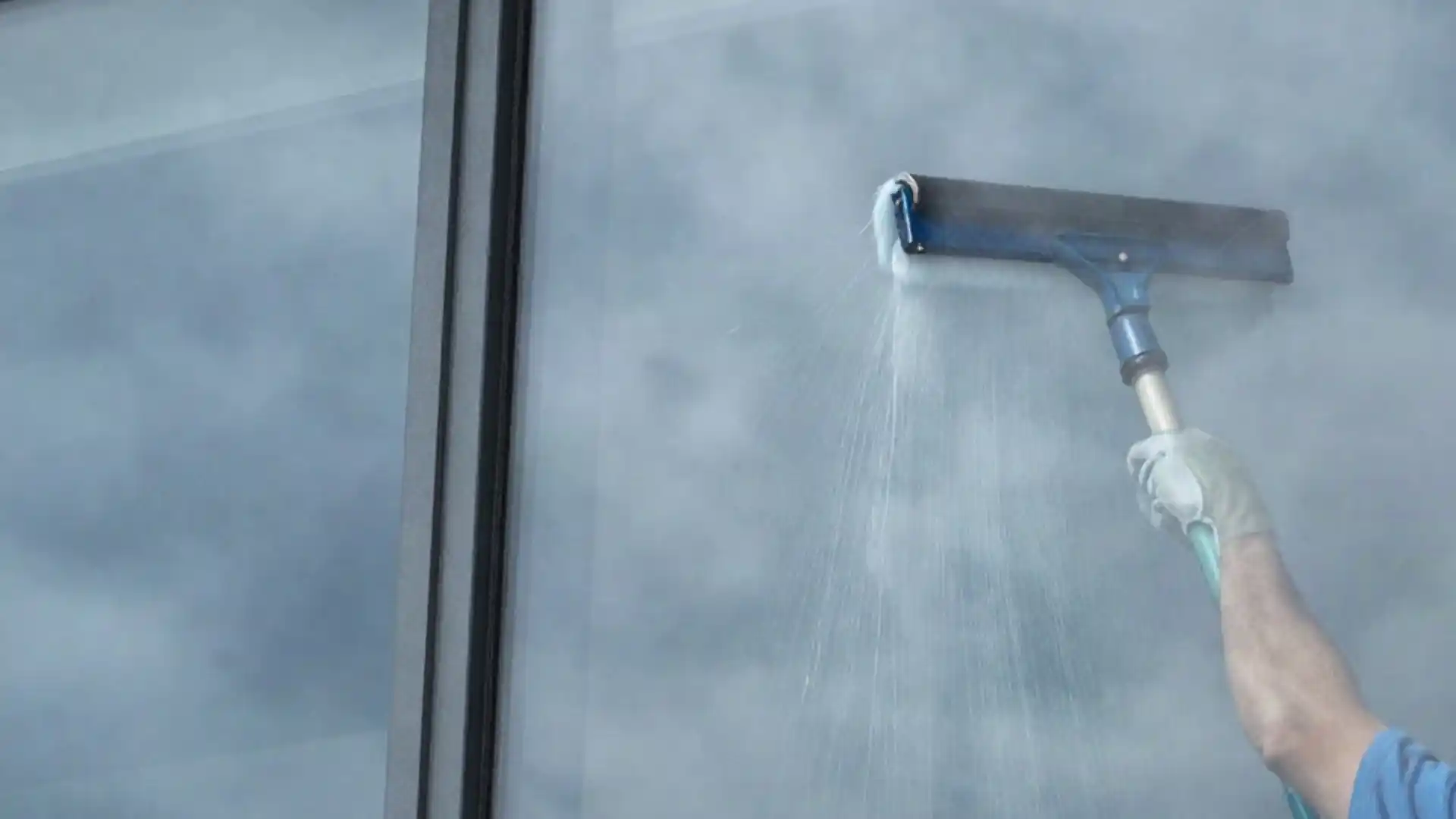 Cleaning tall commercial windows with a pole-mounted scrubber