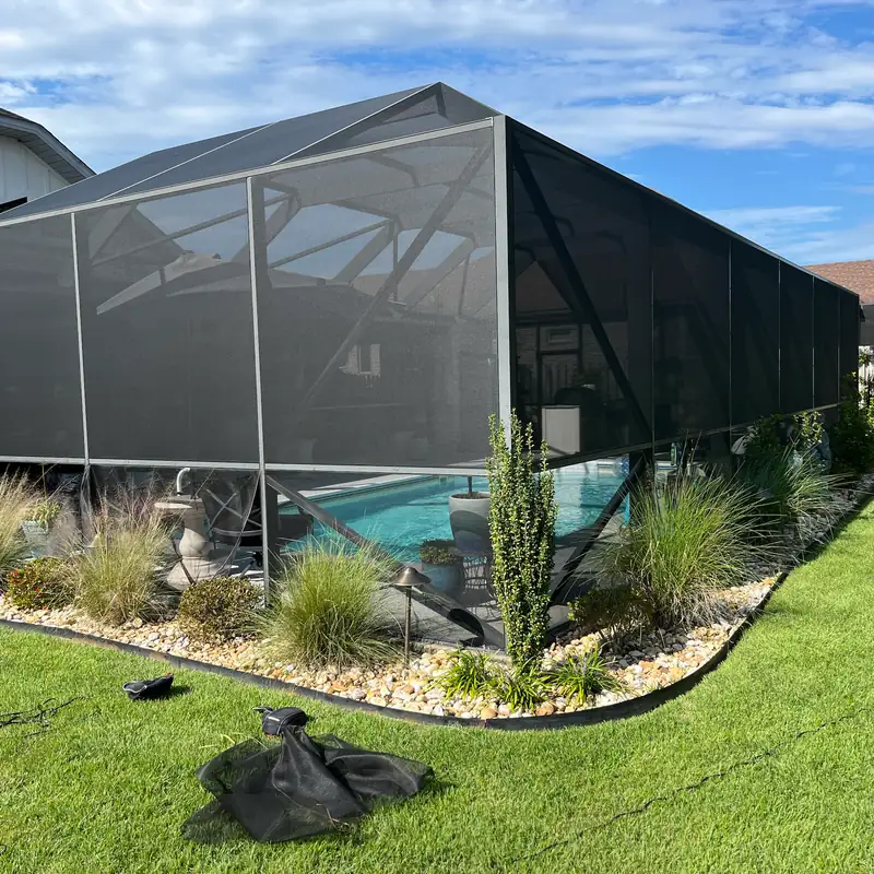 Pool cage mid-rescreen, with the old screen pulled off and piled on the lawn