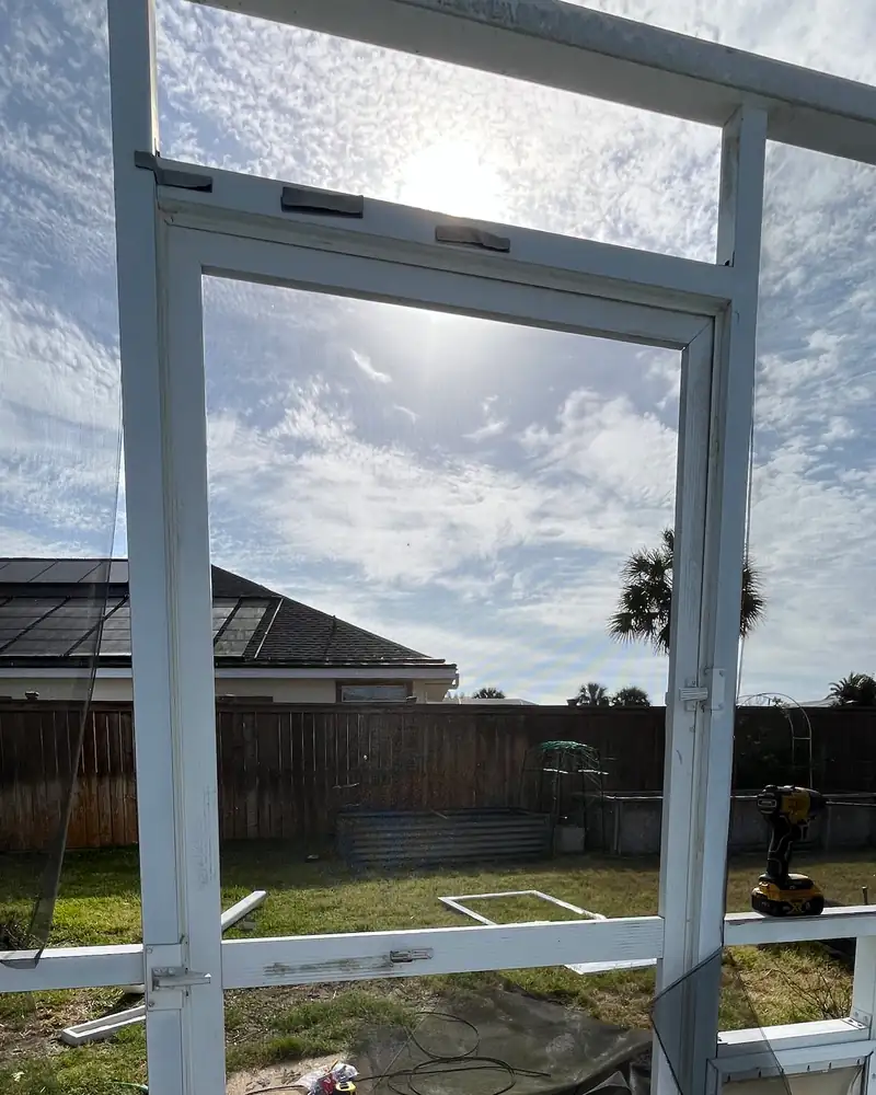 Damaged screen door with a torn screen and a broken bottom panel