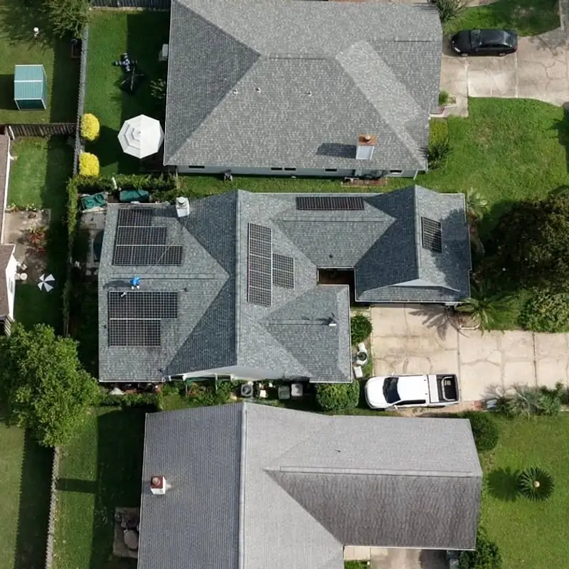 Top-down drone view of a gray roof with solar panels during a cleaning